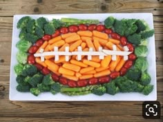 a football made out of carrots, broccoli and hot dogs on a plate