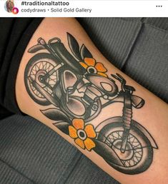 a tattoo on the leg of a person that has a motorcycle and flowers on it