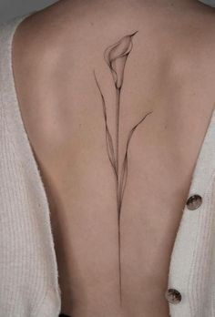 the back of a woman's neck with a flower tattoo on it