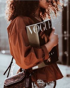 a woman with curly hair is holding a book