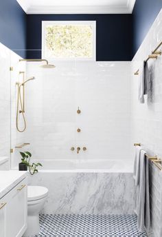 a bathroom with blue and white walls, tile flooring and a tub in the corner