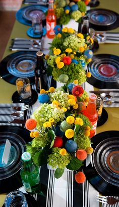 the table is set with black plates and colorful centerpieces