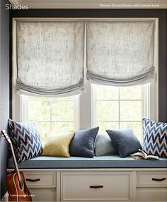 a window seat with pillows on it in front of the windowsill and two guitars