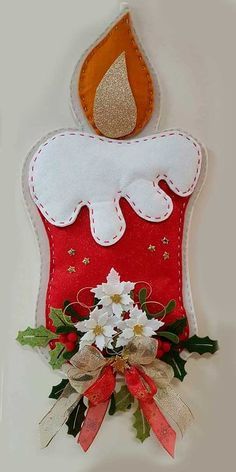 a red and white christmas stocking hanging on the wall with flowers in front of it