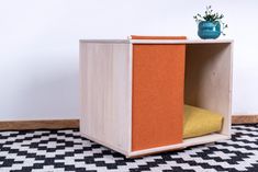 a small wooden box with a plant in it sitting on a black and white checkered floor