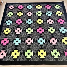 a quilt made with different colors and shapes on a black blanket, sitting on top of a table