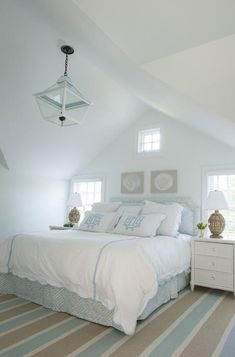 a bedroom with white and blue bedding, striped carpet, two nightstands and a chandelier hanging from the ceiling