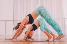 two women doing yoga poses on the floor