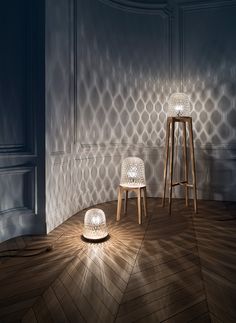 two stools sitting on top of a wooden floor in front of a wall with shadows