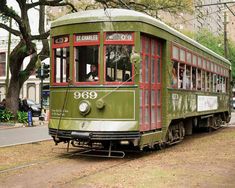 an old green trolley car is on the tracks