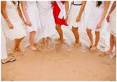 a group of people standing on top of a sandy beach next to the ocean with their feet in the water