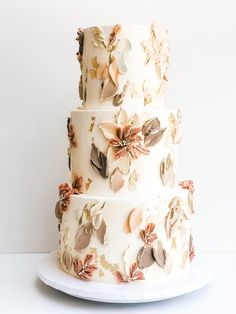 a three tiered wedding cake with flowers on the top and bottom, sitting on a white plate