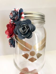 a hand holding a mason jar filled with paper flowers and gold foil on the lid