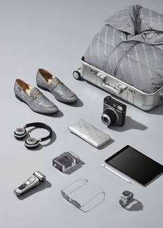 an assortment of silver items including shoes, camera and other accessories are laid out on a gray surface