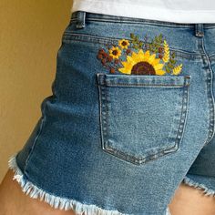 the back of a woman's jean shorts with sunflowers on it