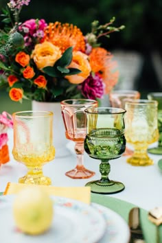 colorful glassware on a table with flowers in the background