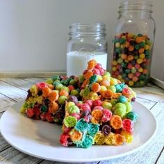 a white plate topped with lots of cereal next to a glass jar filled with milk