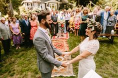 a bride and groom hold hands as they stand in front of an outdoor wedding ceremony