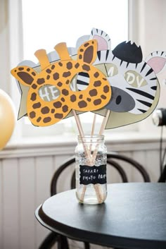 a jar filled with zebra and giraffe cutouts on top of a table