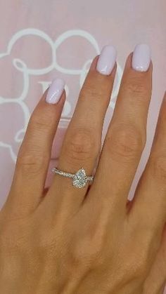 a woman's hand with a diamond ring on her finger and white manicures