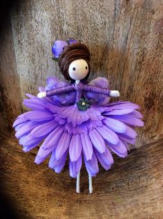 a doll is sitting on top of a purple flower