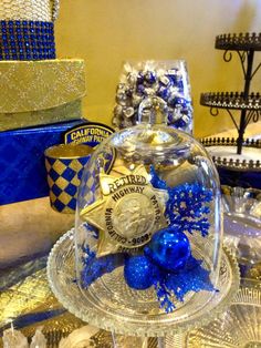 blue and gold decorations under a glass clochet on a table with other items