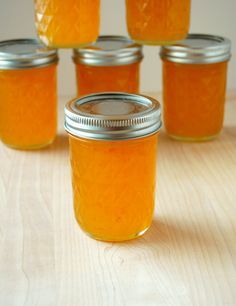 six jars filled with orange liquid sitting on top of a wooden table