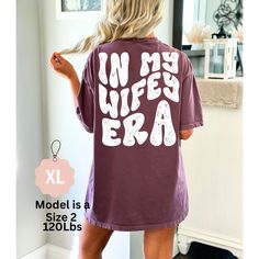 Just in.. Our new Retro Wifey Shirts are Comfy and printed on the best selling brand Comfort Colors.   ~ PRODUCT DETAILS ~ ❤ Comfort Colors Brand ❤ 100 % Cotton ❤ DTG (Direct to Garment) Printing. The Ink is printed directly into the fabric. There is no Vinyl used. ~ SIZING ~ ❤ Unisex Sizing ❤To achieve the Oversized look, please size up 1-3 Sizes. ❤ Please refer to size guide in product images to ensure you are choosing the correct fit. ~ CARE INSTRUCTIONS ~ ❤ Wash inside out with cold water ❤ Lay flat to dry ❤ Do not dry clean ❤ Try to avoid ironing the design ❤ Tumble dry low ~ RETURNS/EXHANGES ~ ❤ Please note; your product is made to order & Returns/Exchanges are not accepted. ❤ Please make sure all sizing & Shipping information is correct before ordering. ❤ We are not responsible for Purple Slogan Tops, Purple Tops, Wife Of The Party Shirt, Taylor Swift Is My Wife Shirt, In My Wife Era Shirt, My Wife Is Dope Shirt, Wifey And Hubby Shirt, Funny Wife Shirts, Retro Bride