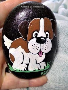 a hand painted rock with a brown and white puppy on it's face is shown