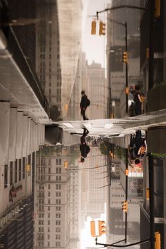 the reflection of people walking down an alley way in front of tall buildings and skyscrapers