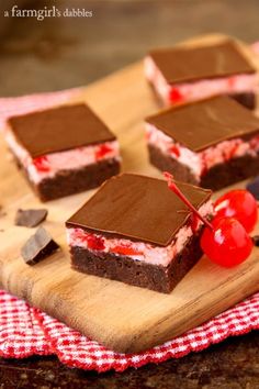 four pieces of cake on a cutting board with cherries