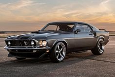 an old mustang muscle car parked on the tarmac at sunset or dawn with clouds in the background