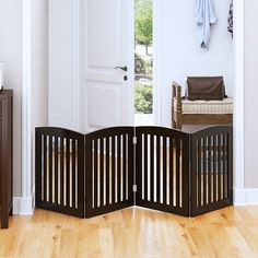 an open room divider in front of a white door with wood floors and wooden furniture