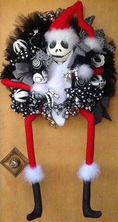 a skeleton wreath with black and white decorations hanging on a door handle in the shape of a santa hat