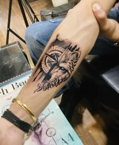 a man's arm with a compass tattoo on it and a wolf in the middle