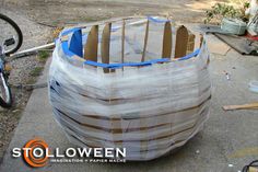 a large wooden barrel sitting on top of a cement ground next to a bike and other items