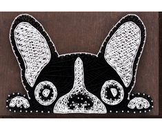 a black and white drawing of a dog's head on a wooden plaque with beads