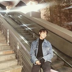 a man sitting on an escalator smiling at the camera with his hands in his pockets