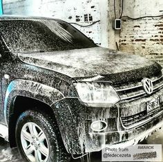 a black truck parked in front of a brick building with snow on the hood and windshield