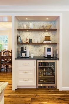 a kitchen with white cabinets and black counter tops, an oven and coffee maker in the corner