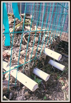 some white pipes are in the ground by a fence