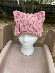 a pink knitted hat sitting on top of a white head mannequin's head