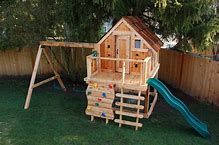 a wooden playset with a slide and climbing frame in the back yard next to a tree