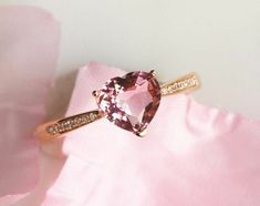 a pink diamond ring sitting on top of a pink cloth