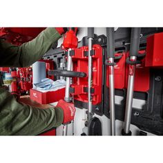 a man working on some red tools in a garage with other tools and equipment behind him