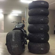 several tires stacked on top of each other in front of a motorbike and scooter