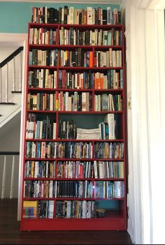 a bookshelf filled with lots of books next to a stair case in a house