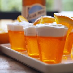 orange juice in cups with lemon wedges on a plate next to a beer bottle