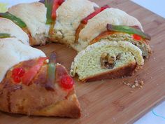 a wooden cutting board topped with lots of bread and toppings on top of it