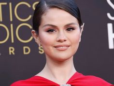 a woman in a red dress posing for the camera with her hair up and eyes closed